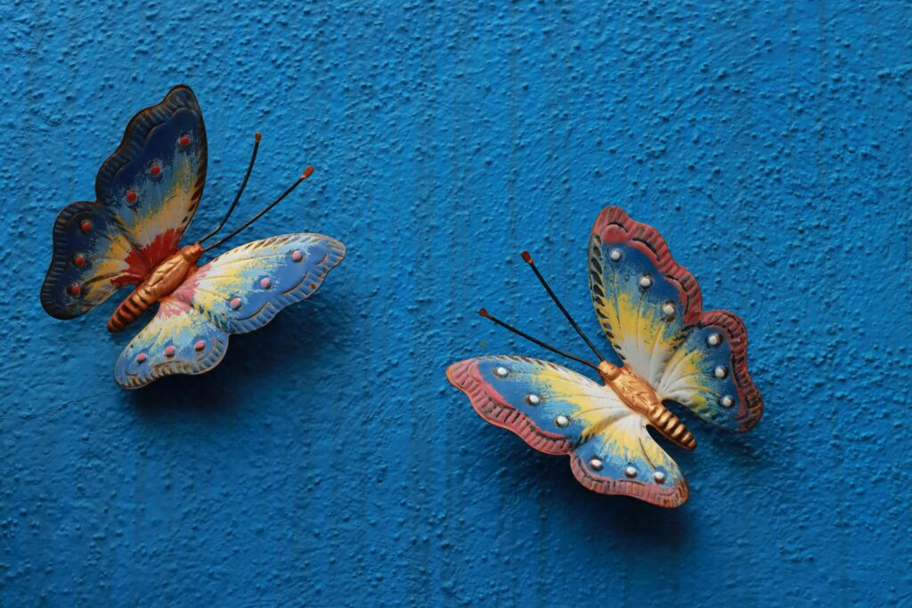 Vibrant handmade butterfly decorations on a textured blue wall in Venice.